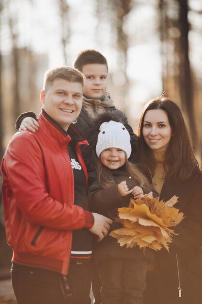 Stockfoto portret van een mooie vrolijke familie met zoon en dochter die een bos gele bladeren houden en lachen om de camera. vrolijke blanke familie samen in zonnig herfstpark.