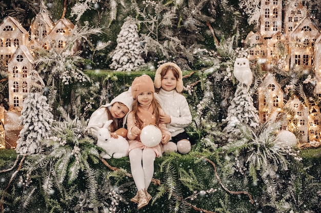 Stockfoto van schattige drie zussen die samen knuffelen, omringd door prachtige kerstversieringen.