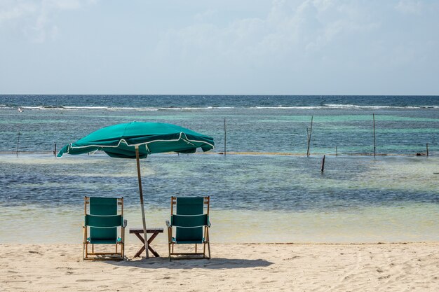 Stoelen en een grote parasol op het strand op een heldere zonnige dag