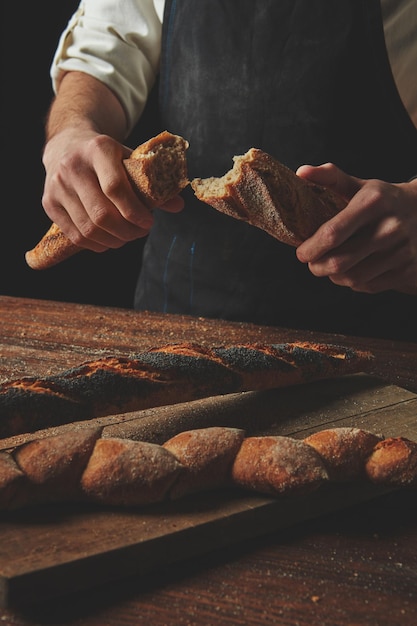 Stokbrood in de handen van een man verdeeld in helften
