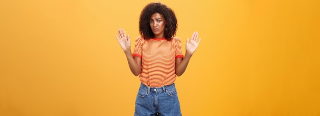 Stom onzeker en verdrietig donkerskinnig vrouwelijk model in trendy gestreepte t-shirt en korte broek met de armen omhoog in