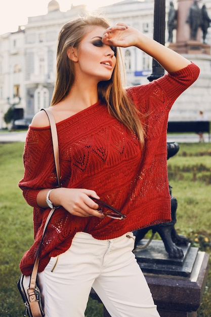 Straat portret van een jonge mooie elegante vrouw in rode trui.