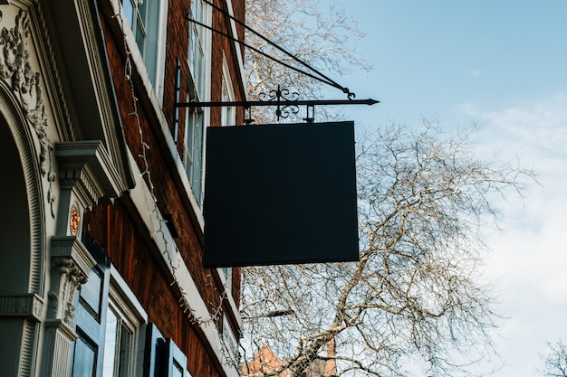 Gratis foto straatlandschap van een zwart leeg teken dat van een gebouw hangt