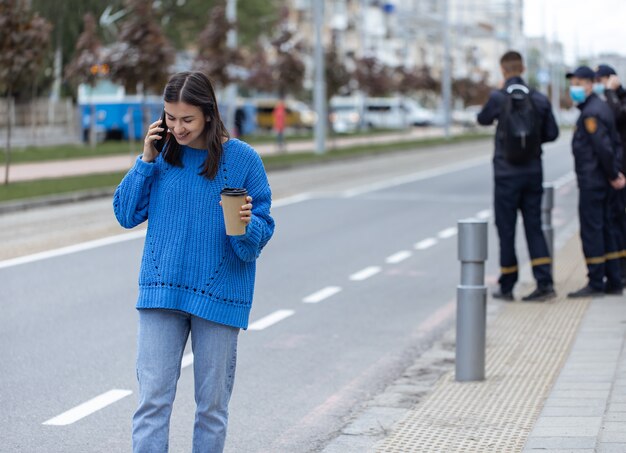 Straatportret van een jonge vrouw die aan de telefoon praat in de stad bij de rijbaan the