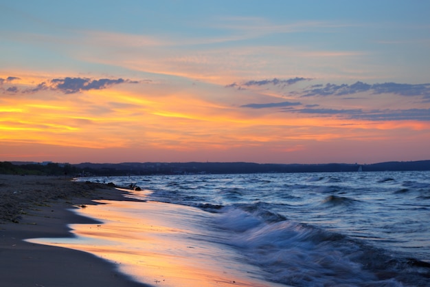 Strand bij zonsondergang met wolken