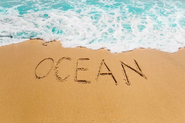 Strandachtergrond met oceaan die in zand wordt geschreven