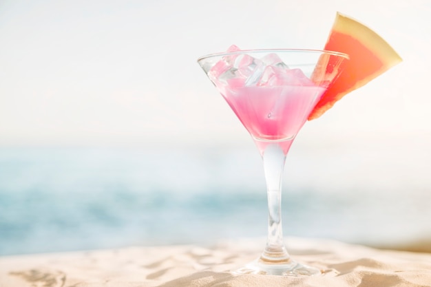 Strandachtergrond met roze cocktail en watermeloen