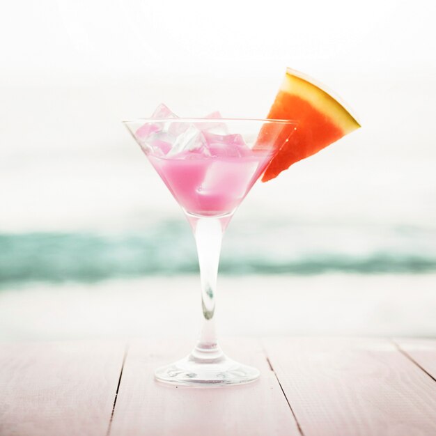 Strandachtergrond met roze cocktail en watermeloen