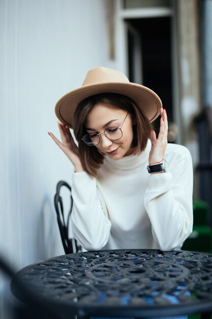 Street fashion tedere vrouw met rode manicure en transparante glazen zitten aan de tafel