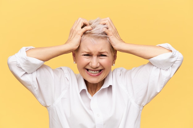 Stress, problemen, woede, woede en negatieve emoties. Gefrustreerde wanhopige rijpe vrouw die schreeuwt en haar aftrekt, boos is op mislukking, gestrest door financiële problemen, haar geduld verliest