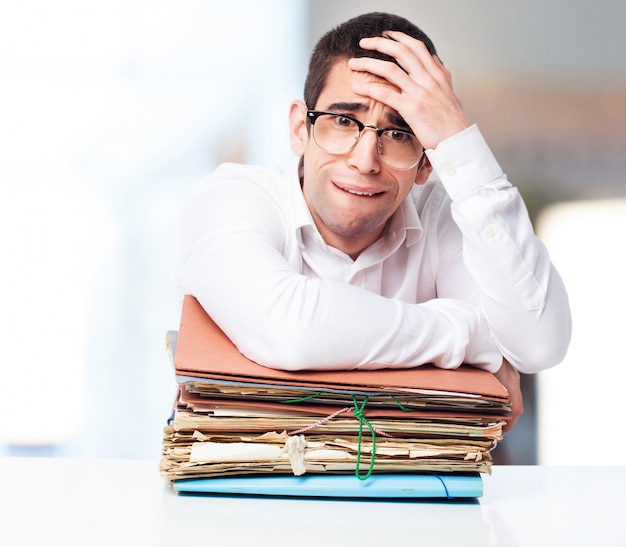 Gratis foto stressed man kijkt naar een stapel papieren met één hand op het voorhoofd