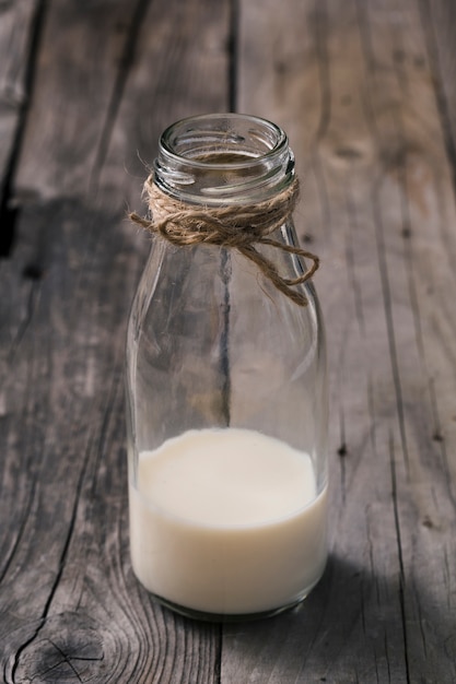 Gratis foto strijk over de glazen fles melk op de oude houten tafel