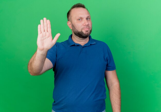 Gratis foto strikte volwassen slavische mens die stopgebaar doet dat op groene muur met exemplaarruimte wordt geïsoleerd