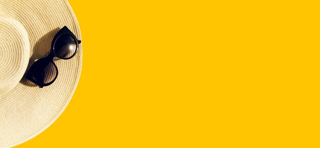 Strohoed met zonnebril op geel
