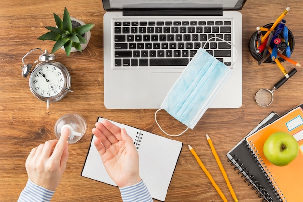 Student gebruikt ontsmettingsmiddel boven bureau