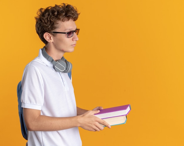 Student man in casual kleding met koptelefoon met bril met rugzak met boeken