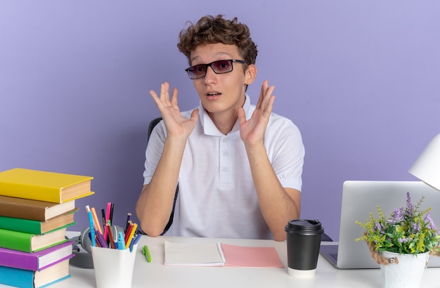 Student man in wit poloshirt met bril aan tafel zitten