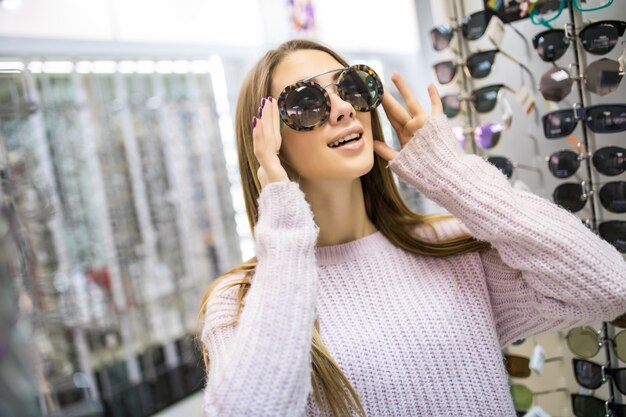 Student meisje bereidt zich voor op studie en probeert een nieuwe bril voor haar perfecte look in de professionele winkel
