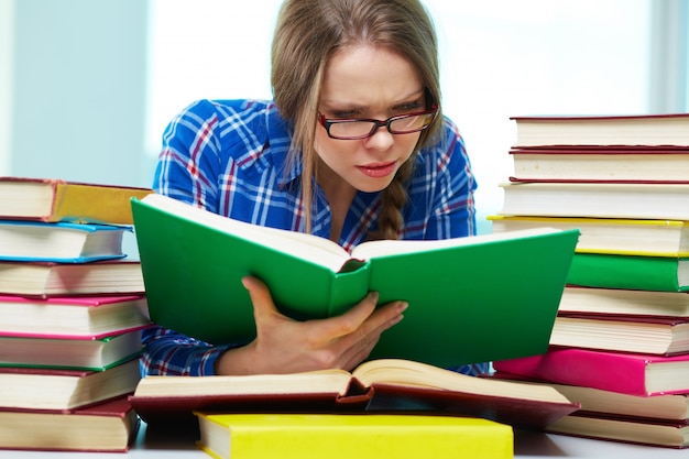 Student met een bril lezen van verschillende boeken tegelijk