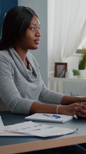 Student met zwarte huid die online cursussen doorbladert en schoolhuiswerk schrijft op de computer tijdens universitaire webinar