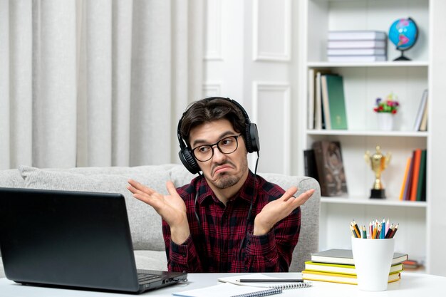 Student online jonge kerel in geruit overhemd met bril die op computer studeert, weet geen antwoord