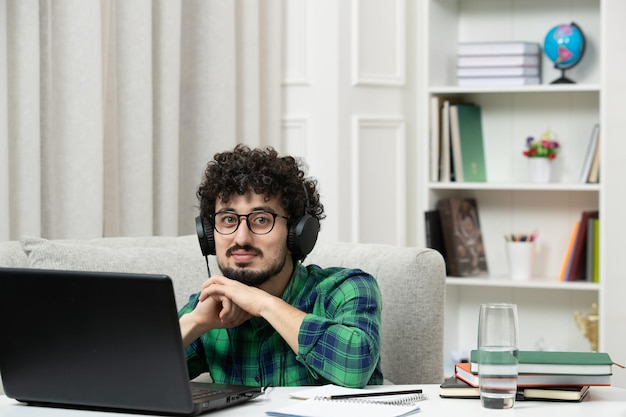 Student online schattige jonge kerel studeren op computer in glazen in groen shirt glimlachend