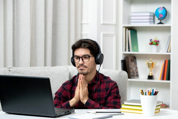 Student online schattige kerel in geruit overhemd met bril studeren op computer bidden