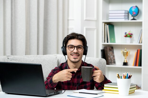 Student online schattige kerel in geruit overhemd met bril studeren op computer met een kopje koffie