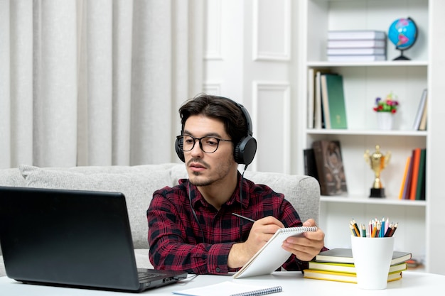 Student online schattige kerel in geruit overhemd met bril studeren op computer notities opschrijven