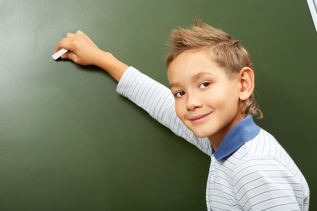 Student schrijven op het bord met krijt