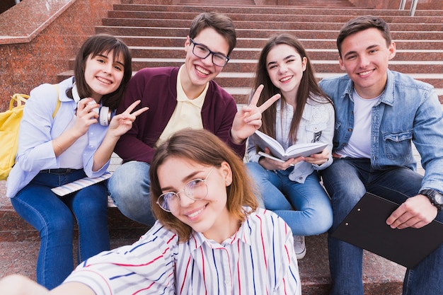 Studenten die op treden zitten en twee vingers gesturing die camera bekijken