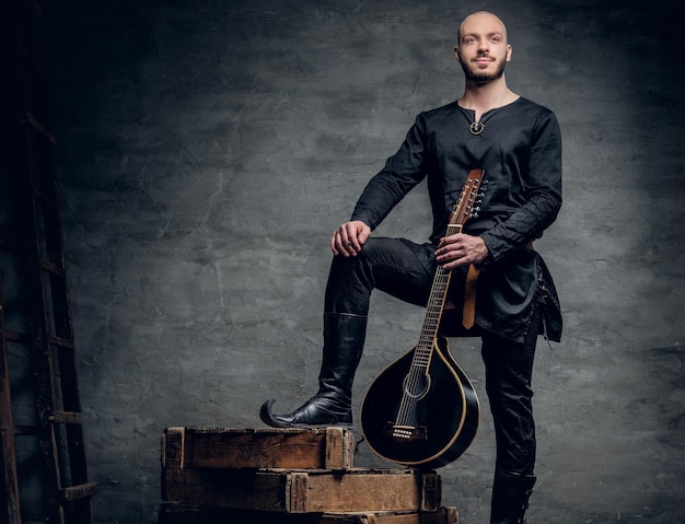 Studio afbeelding van mannelijke muzikanten in oude traditionele keltische kleding houdt vintage mandoline.