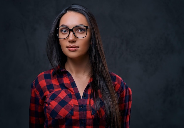 Studio portret van brunette vrouw in brillen gekleed in een rood shirt over grijze achtergrond.