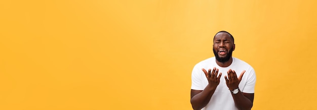 Gratis foto studio portret van jonge afro-amerikaanse man in wit overhemd hand in hand in gebed kijkend naar de