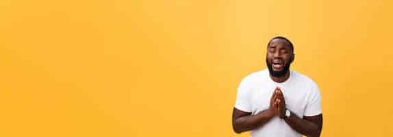 Gratis foto studio portret van jonge afro-amerikaanse man in wit overhemd hand in hand in gebed kijkend naar de