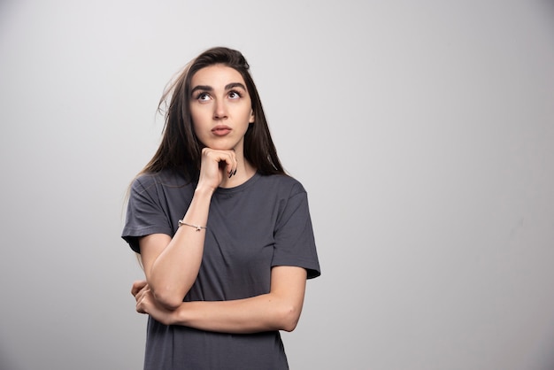 Studio portret van jonge vrouw denken en naar boven kijken.