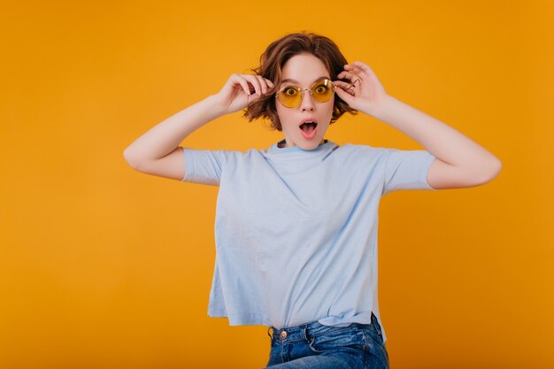 Studio portret van prachtige vrouw in lichtblauw t-shirt verbazing uiten