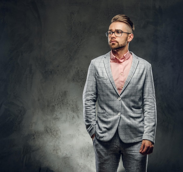 Studio shoot van stijlvolle aantrekkelijke man in geruit pak, bril en roze shirt. Hij stak een hand in zijn zak.