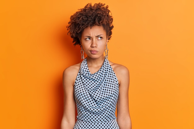 Studio shot van doordachte ontevreden etnische vrouw grijnst gezicht houdt niet van opzij geconcentreerd idee