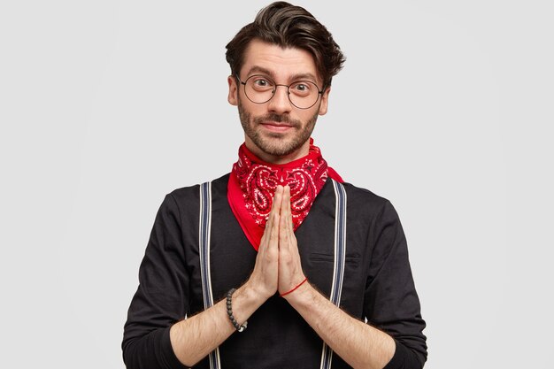 Studio shot van geconcentreerde bebaarde man houdt de handpalmen tegen elkaar gedrukt