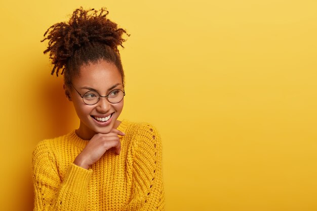 Studio shot van opgetogen vrouw raakt kin zachtjes