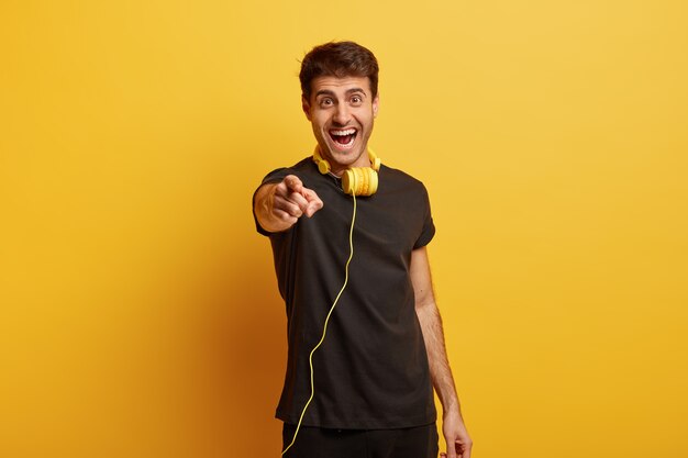 Studio shot van vrolijke hipster man maakt keuze strekt zich uit voorvinger op camera