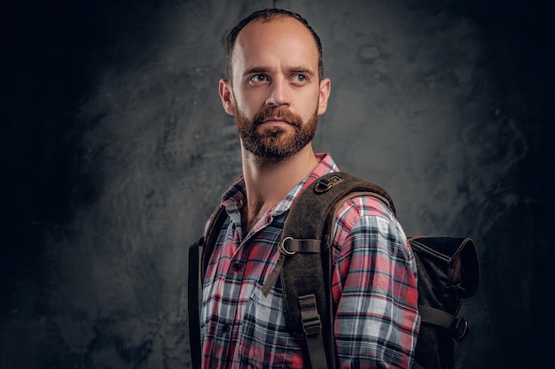 Studioportret van bebaarde man in een shirt met rugzak.