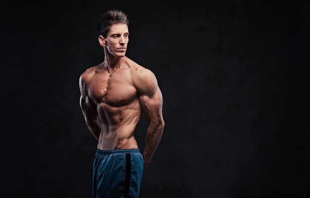 Studioportret van de ectomorph shirtless man toont zijn triceps.