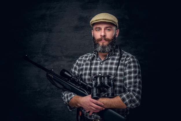Studioportret van een bebaarde jager houdt een geweer vast.