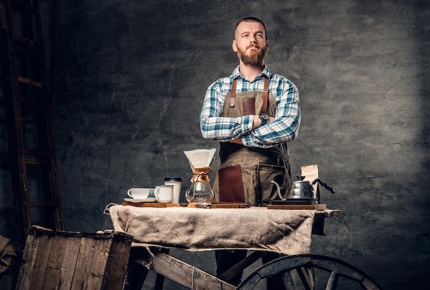 Gratis foto studioportret van roodharige bebaarde man aan tafel met automatisch koffiezetapparaat.