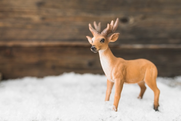 Gratis foto stuk speelgoed herten op sneeuw dichtbij houten muur