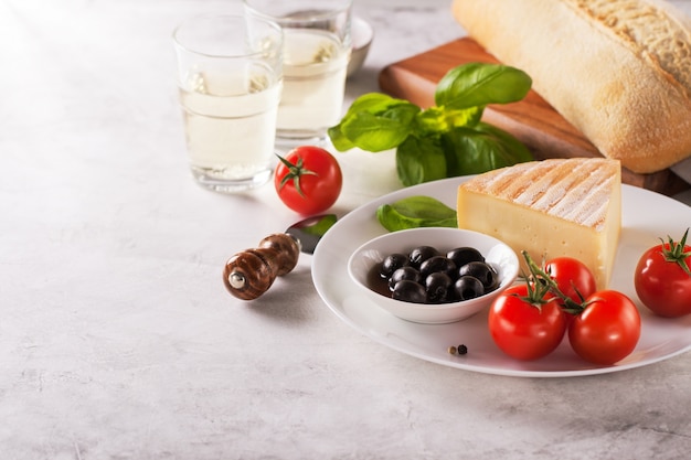 Stuk van kaas met tomaten en zwarte olijven op een bord