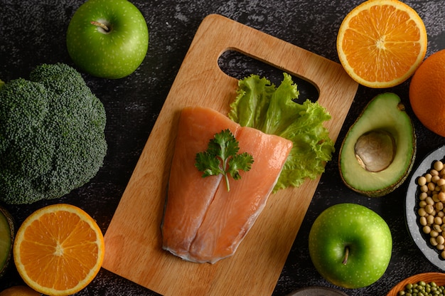 Stukjes peulvruchten, fruit en zalmvissen op een houten snijplank.