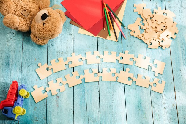 Stukjes puzzels op het oppervlak van een houten tafel met speelgoed en kleuren